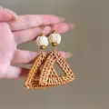 Close-up of handmade brown rattan woven triangle earrings with white textured beads - #9 Silver Needle - Brown - Triangle