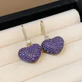 Elegant close-up of sparkly purple pavé crystal heart earrings in a beige jewelry box. - Gold Ear Hook / Purple