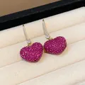 Close-up macro detail of heart earrings with sparkling pink pave zircon crystals - Gold Ear Hook / Pink