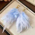 Elegant blue and white feather tassel earrings with pearl studs displayed in a jewelry box - Gold Blue