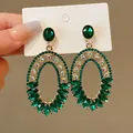 Close-up detail of vintage oversized oval earrings featuring emerald green and clear rhinestones - European American Silver Post Rhinestone Oval Style / Green