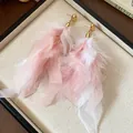 Detailed view of elegant pink and white feather tassel earrings in a cream jewelry box - Pink