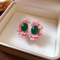 Nahaufnahme von rosa Blumenohrsteckern mit ovalem grünem Stein in einer Geschenkbox. - Ovaler Blumenstil / Rosa und Grün Kontrast