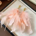 Close-up detail of delicate pink feather tassel earrings with hammered gold studs - Gold Pink