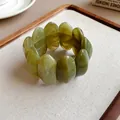 Dettaglio ravvicinato di un bracciale ovale in acrilico verde oliva marmorizzato su vassoio - verde oliva