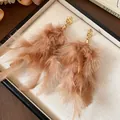 Detailed view of fluffy light brown feather tassel earrings in a box. - Gold & Coffee