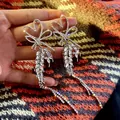 Detailed macro shot of silver heart and bow earrings with long sparkling crystal tassels - Heart Bow Knot Long Tassel (HE6762) / Silver