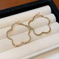 Detailed view of elegant gold flower-shaped hoop earrings resting in a velvet box - Gold