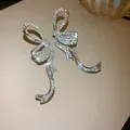 Elegant sparkling rhinestone ribbon bow tassel earrings with a bright silver finish. - Bowknot Tassel (HE15275) / Silver