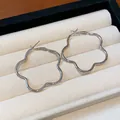 Close-up view of elegant silver-toned flower-shaped hoop earrings in jewelry box - Silver