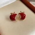 Primo piano di eleganti orecchini a lobo a mela in smalto rosso con accenti di zircone. - Rosso