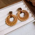 Gros plan de boucles d'oreilles en rotin tressé avec haut en résine ambrée. - Rond (4) / Aiguille en argent / Marron