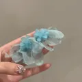 Dettaglio che mostra orecchini a nappa con fiori in tessuto a rete azzurro tenuti in mano - Stile 2 Perno in Argento