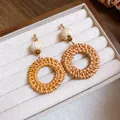 Vue détaillée de boucles d'oreilles bohèmes en rotin avec perles bois et boule de paille - Rond (1) / Tige de boucle d'oreille en acier / Marron