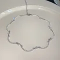 Primer plano de un collar ondulado plateado con brillantes piedras de circonita cúbica. - Plateado