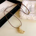 Minimalistische Gold-Croissant-Halskette mit verstellbarem braunem Lederband für Damen - Croissant-Form / Kaffeebraune Kordel - Goldener Anhänger