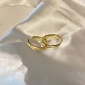 Orecchini a cerchio dorati minimalisti con finitura testurizzata su seta bianca elegante. - Ear Buckle Style 1
