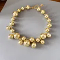 Chunky irregular golden bead necklace with high-gloss metallic finish on grey board - Gold