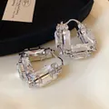 Macro close-up view of minimalist silver U-shaped hoop earrings encrusted with shimmering crystals - U-Shape Bag Style / Silver
