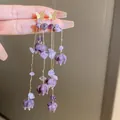 Close-up of elegant purple flower tassel earrings with gold butterfly studs and gems - Purple Butterfly Flower Tassel