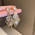 Elegant gold-toned leaf drop earrings with opal-like stone studs and tassel design. - Gold Cat Eye Stone Leaf Tassel