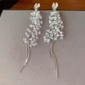 Silver-toned long tassel earrings featuring sparkling clustered stone accents. - Silver
