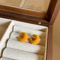 Close-up detail of yellow flocked C-shaped stud earrings featuring a soft velvet texture - Yellow