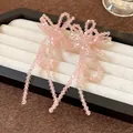 Primo piano di eleganti orecchini a fiocco in perle di vetro rosa con lunghe nappe - Nappina a Fiocco / Rosa