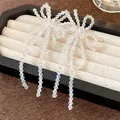 Visuale macro di orecchini a fiocco in perle di vetro con lunghe nappine pendenti - Nappina a Fiocco / Bianco