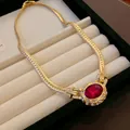 Close-up of vintage gold snake chain necklace with oval red gemstone and rhinestones - Gold with Red Stone