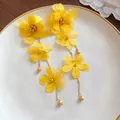 Detailed macro view of vibrant yellow chiffon flower petals on elegant tassel earrings - Yellow