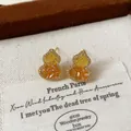 Detailed macro shot of elegant gold-plated gourd earrings with yellow zircon crystals - Light Coffee