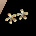 Primer plano de pendientes de flores doradas con un acabado metálico cepillado texturizado - Dorado