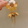 Detailed shot of gold-plated floral earrings featuring long tassels and crystals - Gold