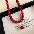 Close-up of Ancora red bead necklace with delicate silver chain on textured paper - 10mm Diameter / Silver/Red