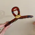 Gros plan sur l'élégante pince à cheveux en résine écaille avec détail étiquette dorée handmade - Style Croisé Café Motif Écaille (HH5276)