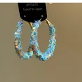 Dettaglio ravvicinato di grandi orecchini a cerchio con paillettes a stella blu chiaro. - Stile Stella Oro Blu
