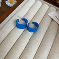 Dettaglio degli orecchini a cerchio a C blu brillante su un espositore in velluto beige - Torsione Onda Blu Scuro Forma C