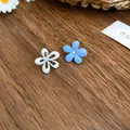 Dettaglio ravvicinato di orecchini a lobo a fiore in smalto blu e bianco per lei. - Fiore Asimmetrico Bianco Blu