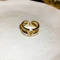 Detailed view of a gold-plated double-layer ring featuring a central V-logo and zircons. - Gold