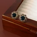 Detailweergave van vintage bloemenoorknopjes met diepblauwe steen op een houten doos - Blauwe Zilveren Naald Oorbellen