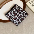 Close-up detail of a retro leopard print fabric bandana folded on a rustic wooden tray - Vintage Leopard Print Style (15#)