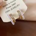 Close-up of 18k gold plated ear clips with pearls and baguette-cut zircons on a card - One Pair / Gold