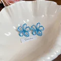 Eleganti orecchini a fiore traforati blu chiaro su vassoio a conchiglia - Fiore a Linea Cava Blu