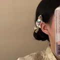 Détail d'une pince à cheveux poisson dorée avec écailles argentées sur des cheveux noirs. - Pince à bec Forme de Poisson