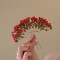 Vue détaillée d'une épingle à cheveux en U tenue à la main avec fleurs rouges artificielles - Épingle à Cheveux en U Gypsophile