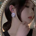 Close-up of a sparkling oval rhinestone earring worn on an ear with a pearl mirror background - Full Rhinestone Round Style (9#) / Gold