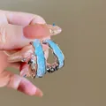 Eleganti orecchini a onde argentati con inserti in resina blu chiaro testurizzata per lei - Cornice in Metallo a Onda Blu