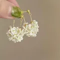 Macro view of elegant white pearl flower cluster earrings with gold chains and ball studs. - Style 10