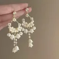 Detailed view of elegant white floral drop earrings with pearls and gold accents - Style 5